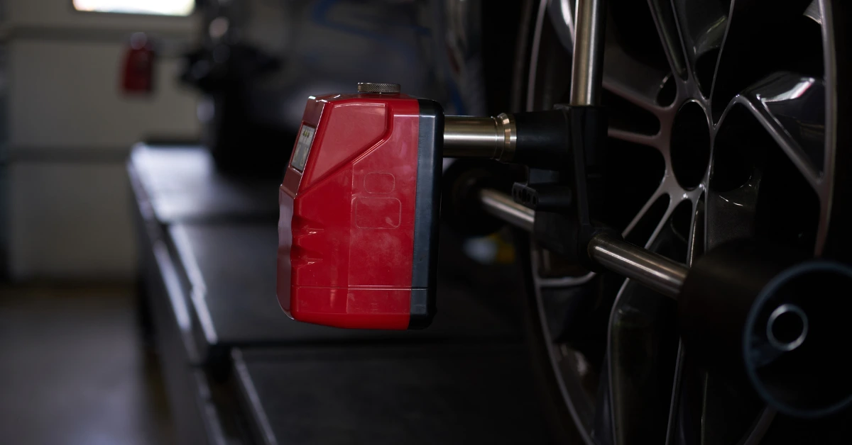 Car wheel on professional alignment rig with digital sensor device, used in workshop to adjust suspension and calculate accurate wheel alignment cost