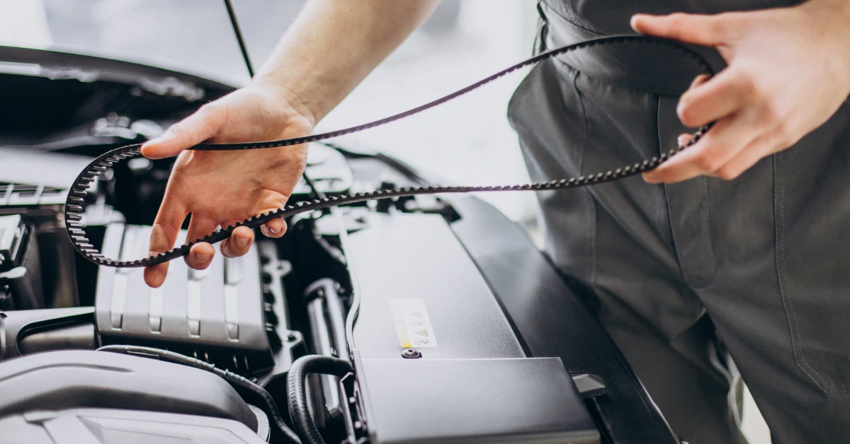 Close-up of a technician removing a timing belt from a car engine during replacement — learn what influences timing belt cost at your workshop.